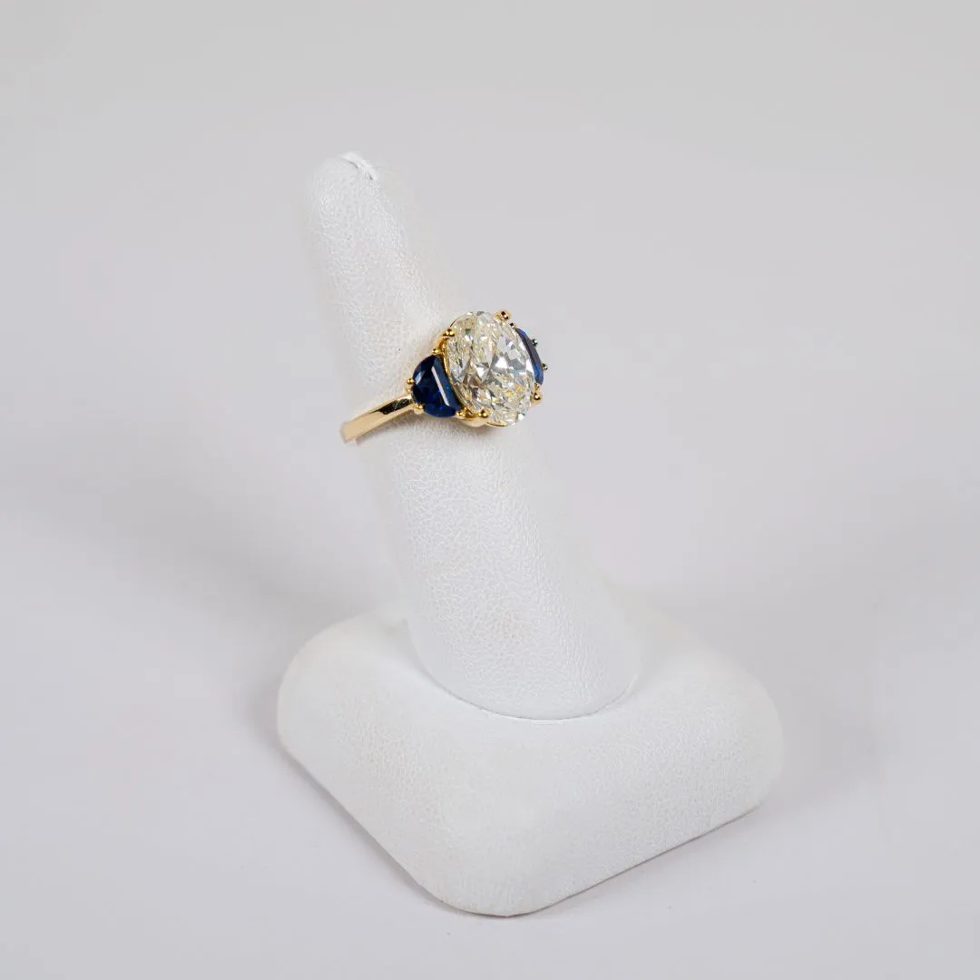  18 Karat Yellow Gold 3 Stone Fashion Ring with a 4.50 Carat Oval Brilliant Shaped Center Diamond and 2 Blue Sapphire Accent Stones Bay Area Diamond Company Green Bay, WI