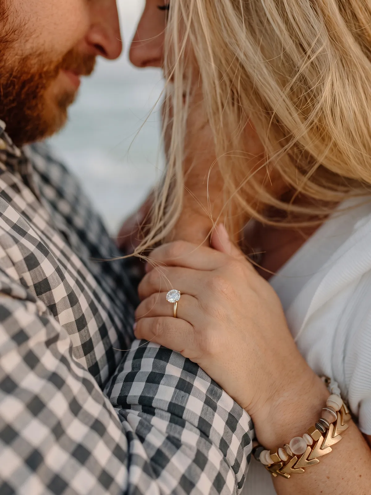 A couple holding hands closely, showing an engagement ring.