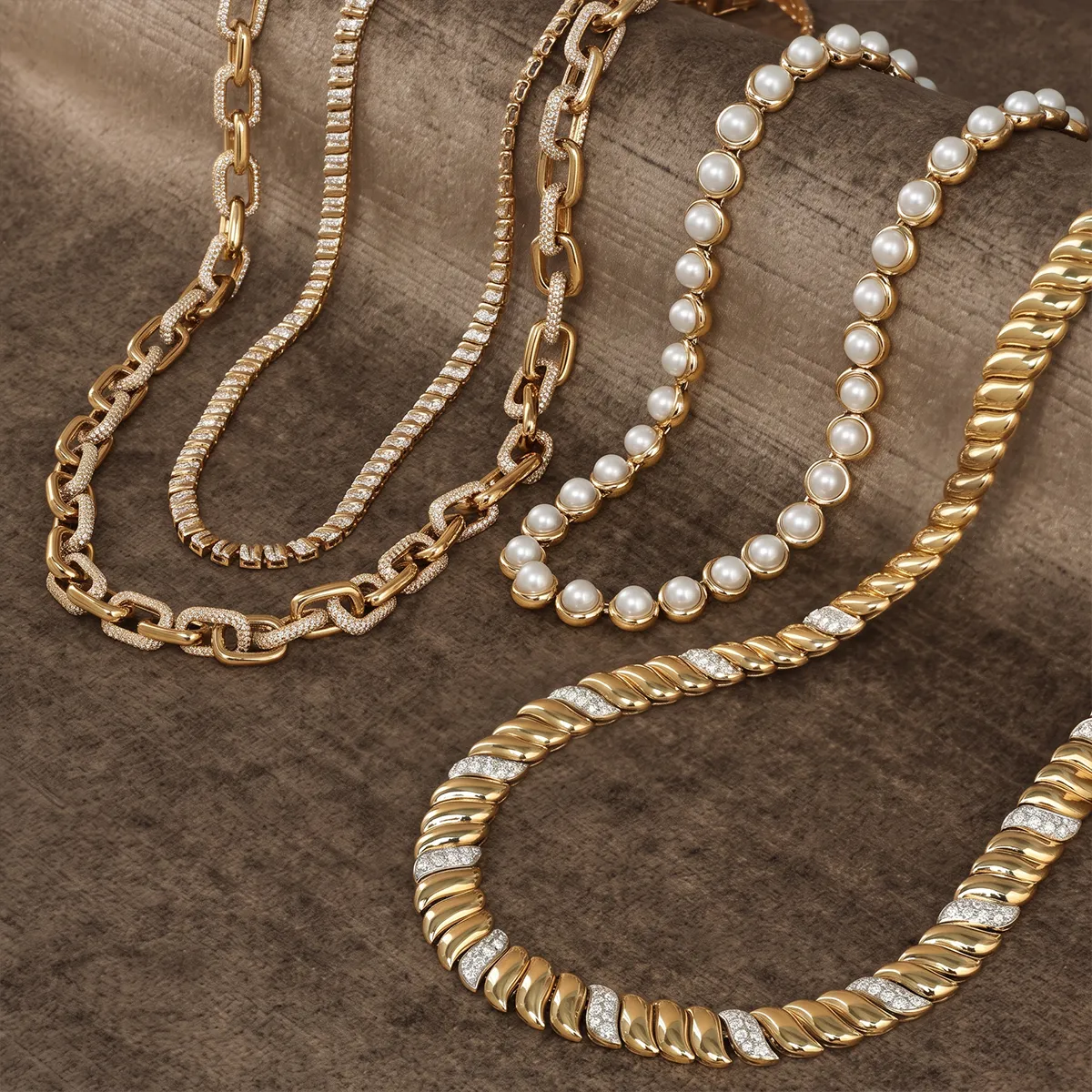 Elegant gold and pearl necklaces displayed on a textured surface.