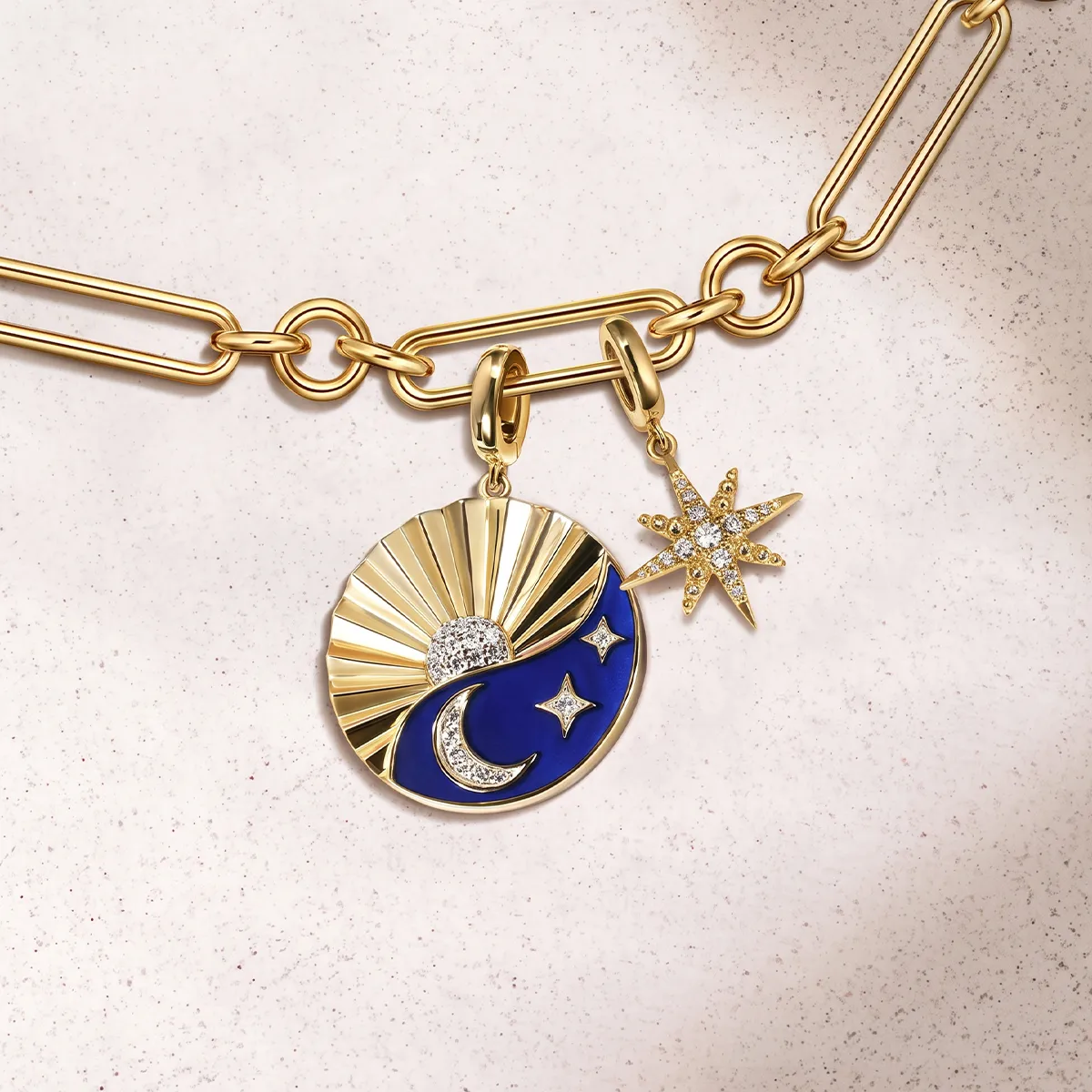 Gold chain with sun, moon, and star charms, featuring blue enamel and sparkling accents.