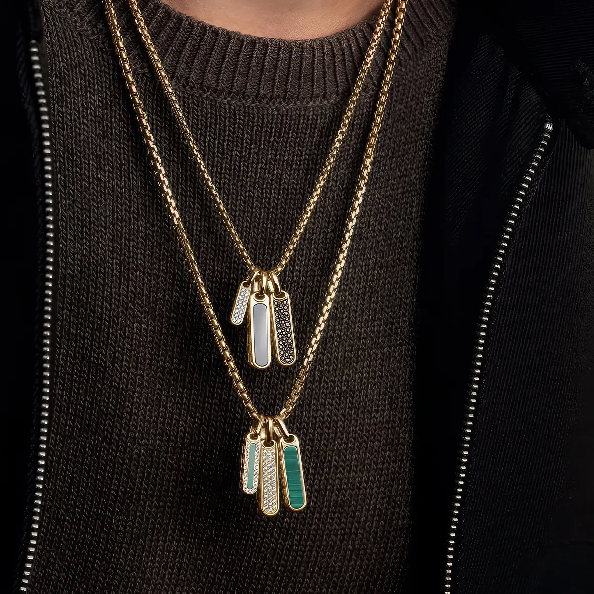 Gold necklaces with multiple rectangular pendants on a person wearing a dark sweater.