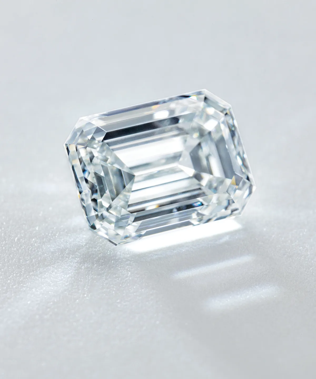 Emerald-cut diamond on a reflective surface, showcasing its clarity and facets.