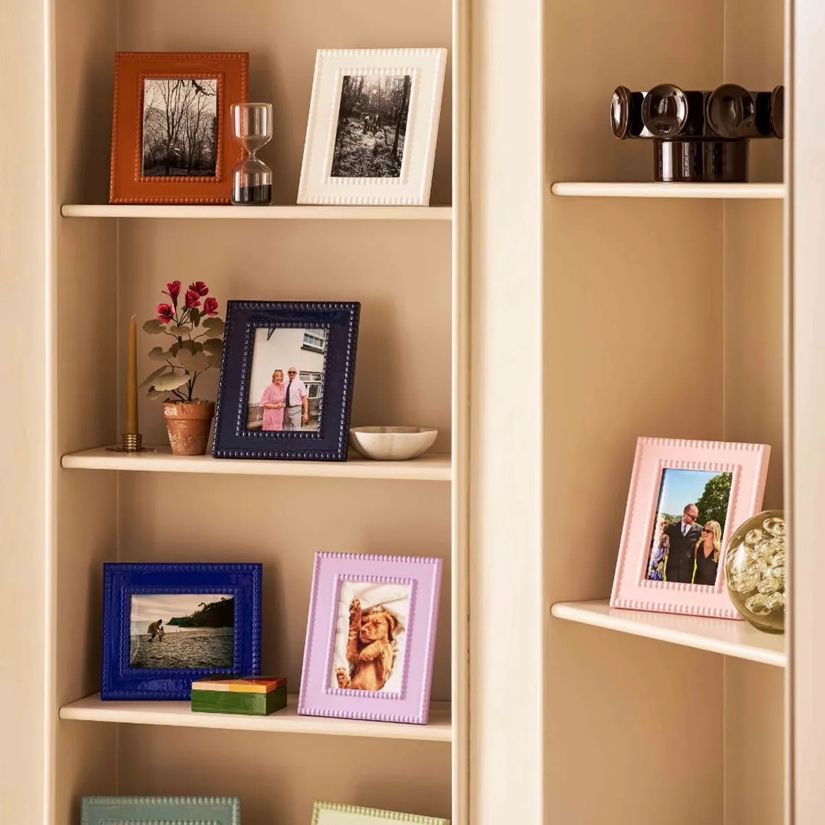 Shelf with colorful photo frames, small decor items, and a sand timer.