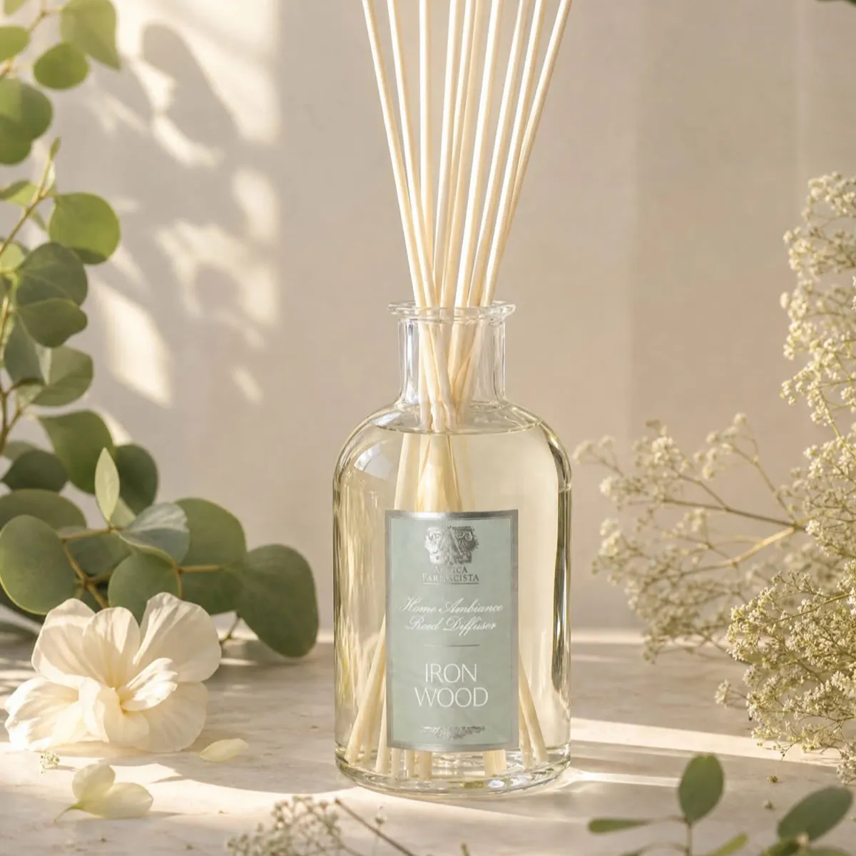 A glass reed diffuser labeled 