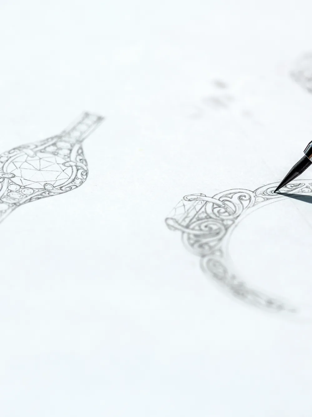 Detailed sketch of intricate jewelry designs with a pen in focus, showcasing artistry in jewelry creation.