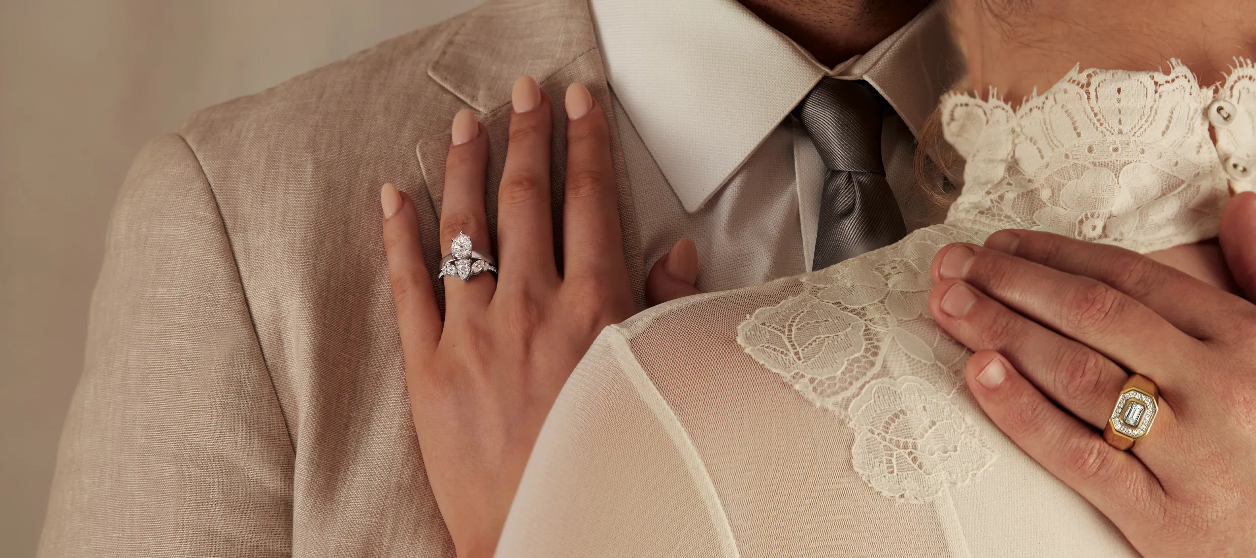Couple embracing, showcasing an elegant engagement ring on the woman's hand.