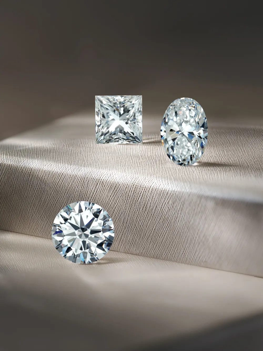 Three sparkling diamonds in different cuts displayed on a soft fabric background at Bethany's Jewelry in Wellsboro.