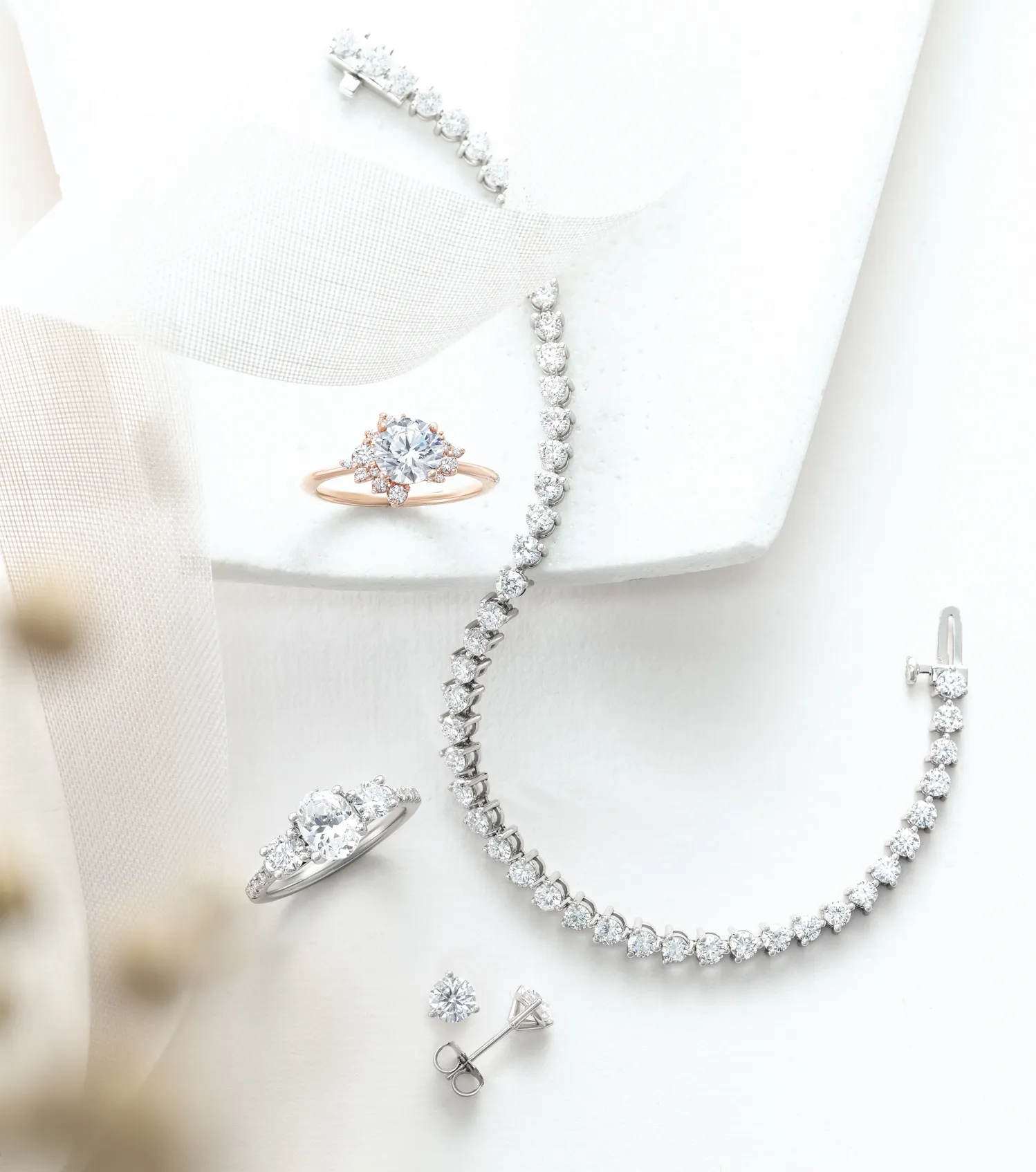 Elegant jewelry display featuring a rose gold ring, silver bracelet, and diamond earrings. Visit Bethany's Jewelry in Wellsboro.