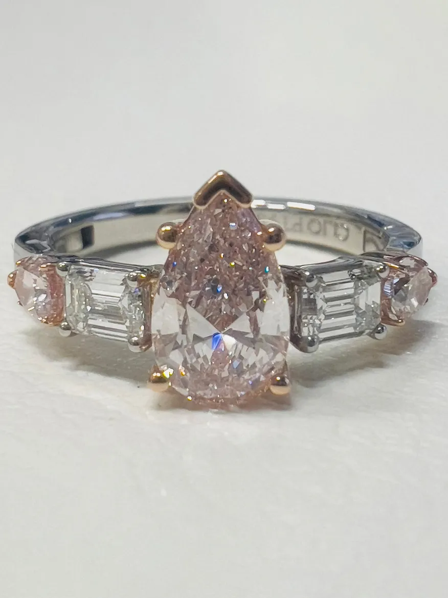 Elegant rose gold engagement ring with a pear-shaped pink diamond center and smaller diamonds on the band.