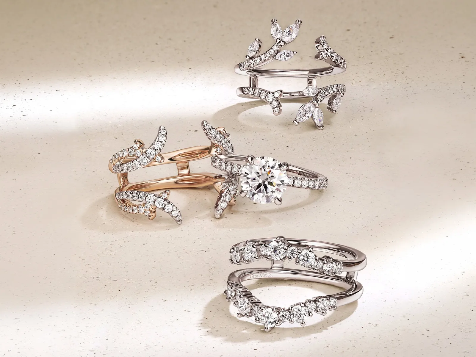 Diamond rings with intricate designs on a textured surface.
