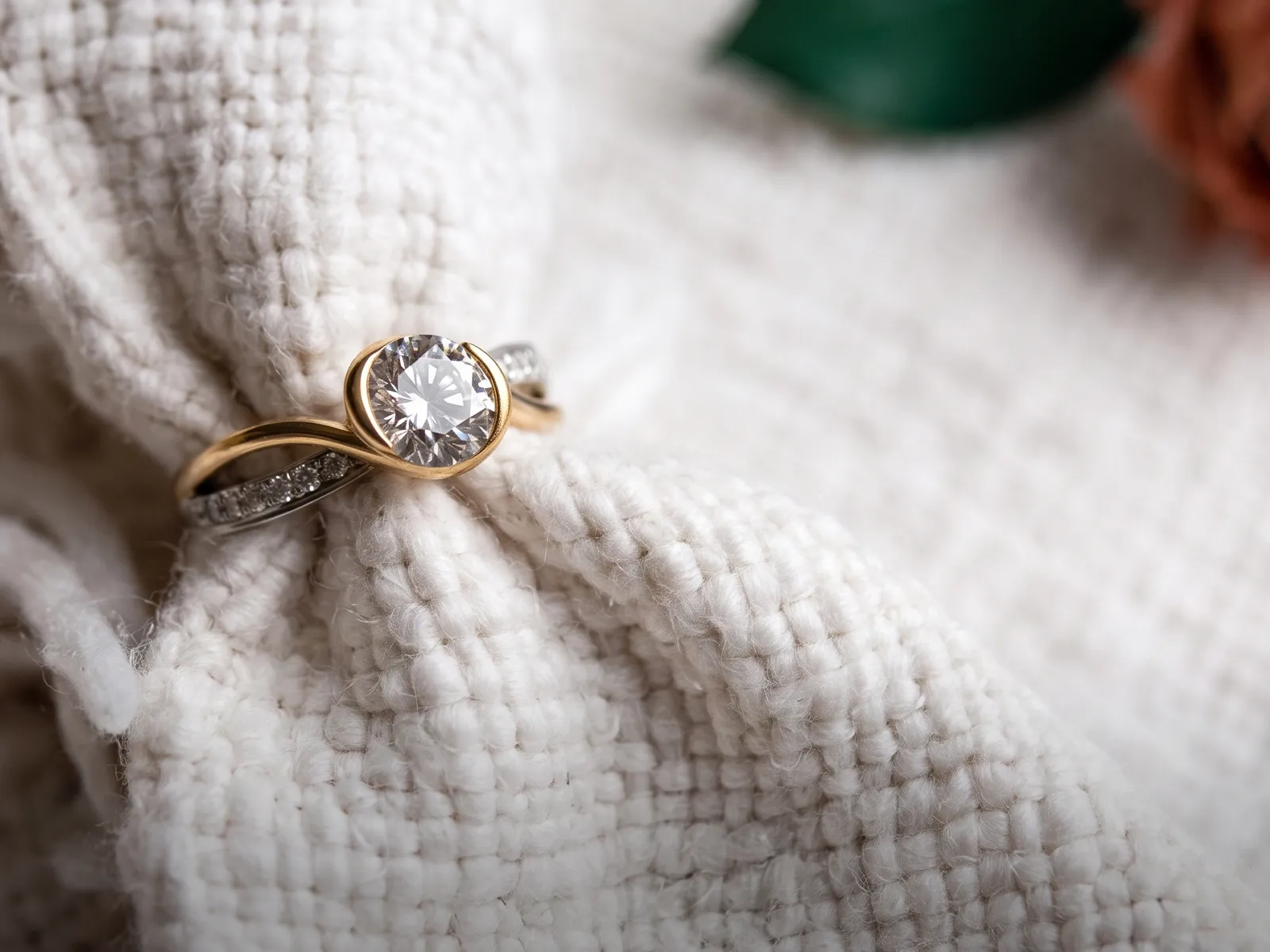 A gold and silver diamond ring on textured white fabric.