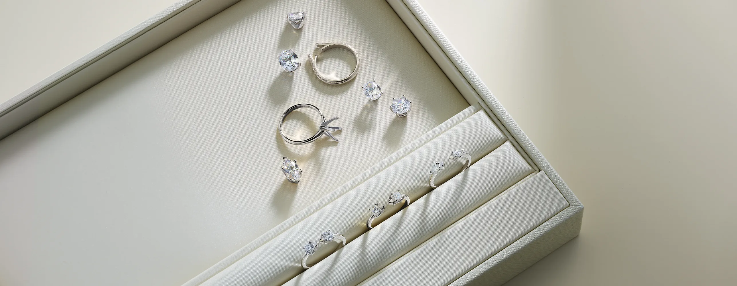 A jewelry box displaying diamond rings and loose stones on a light background.