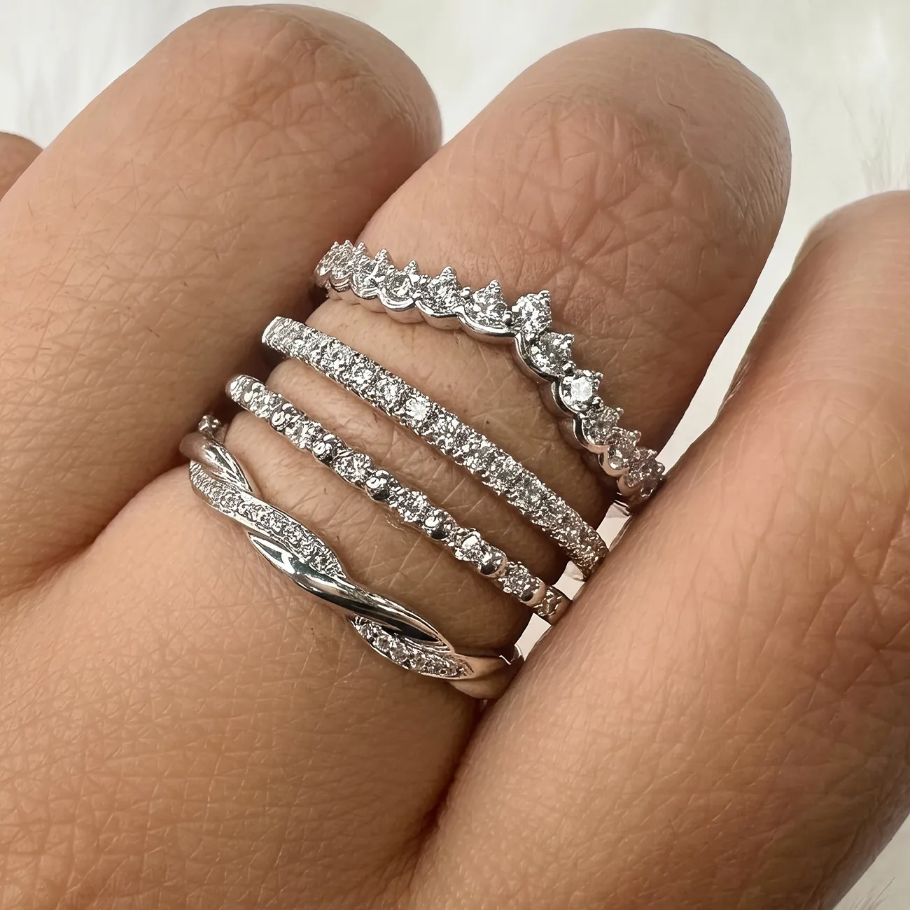 Five diamond-studded rings on a person's fingers, showcasing intricate designs and sparkling stones.