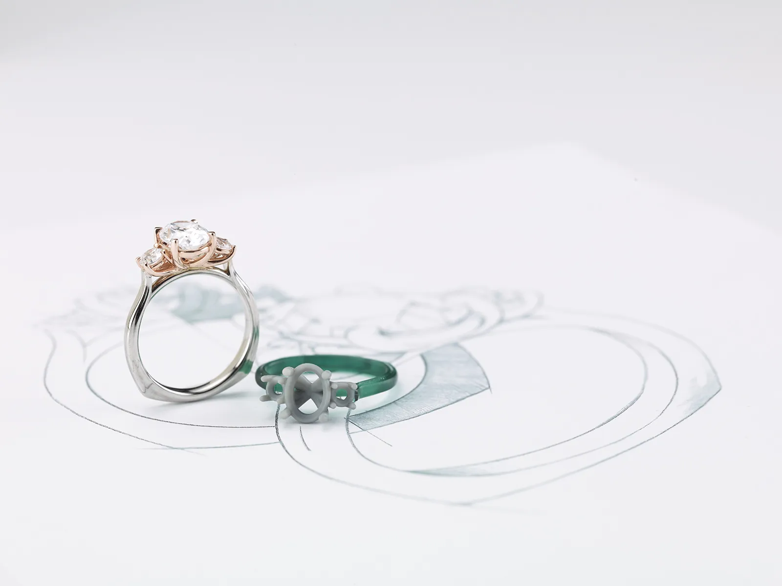 A diamond ring and a green ring mold on a jewelry design sketch.
