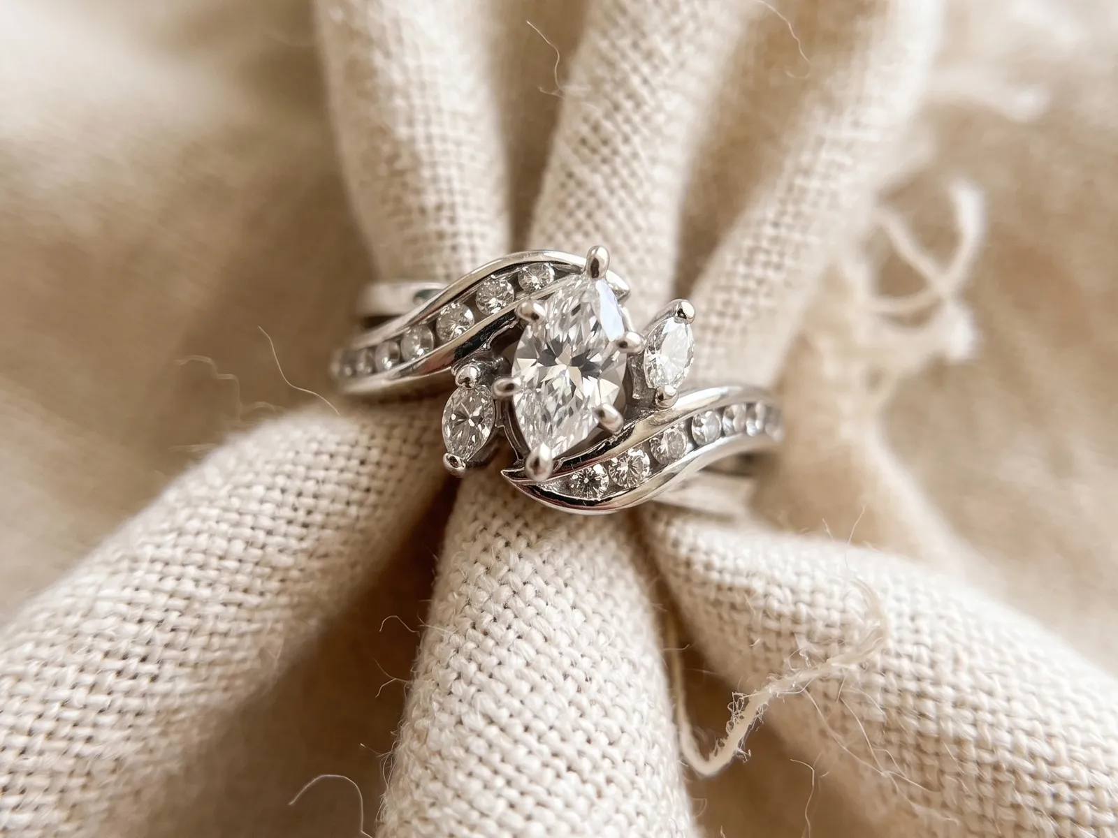 A diamond ring with intricate design on a beige fabric background.