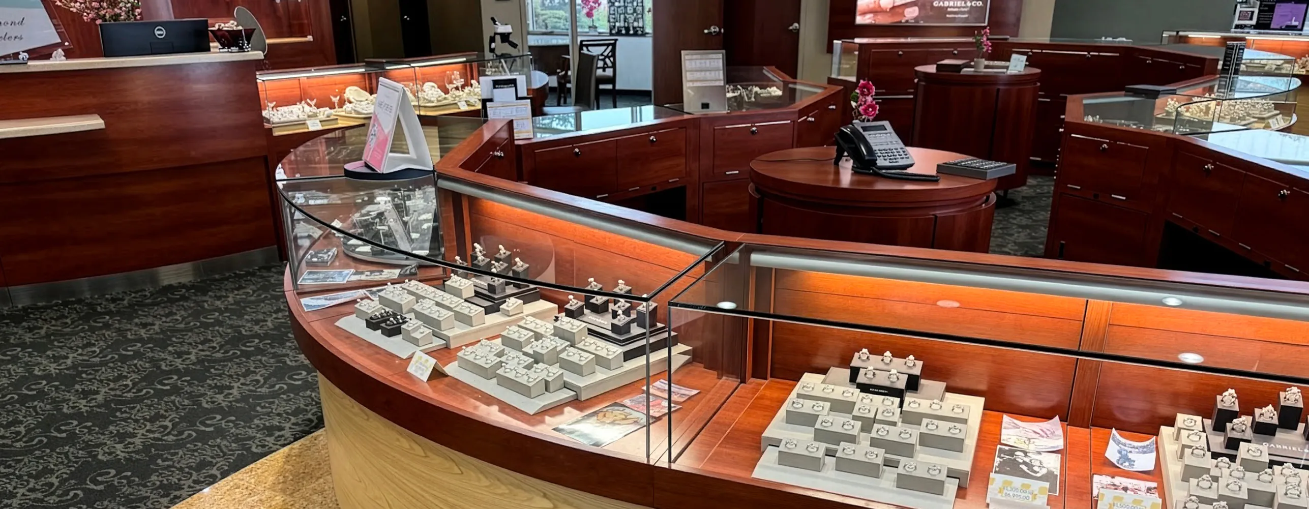 Jewelry store interior with wooden display cases showcasing rings and other jewelry items.