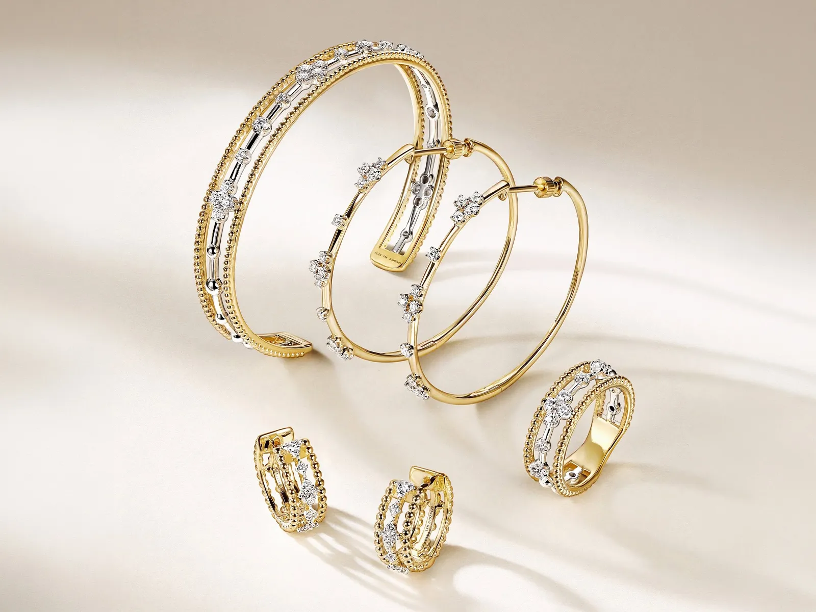Gold and diamond bracelets and rings displayed on a light background.