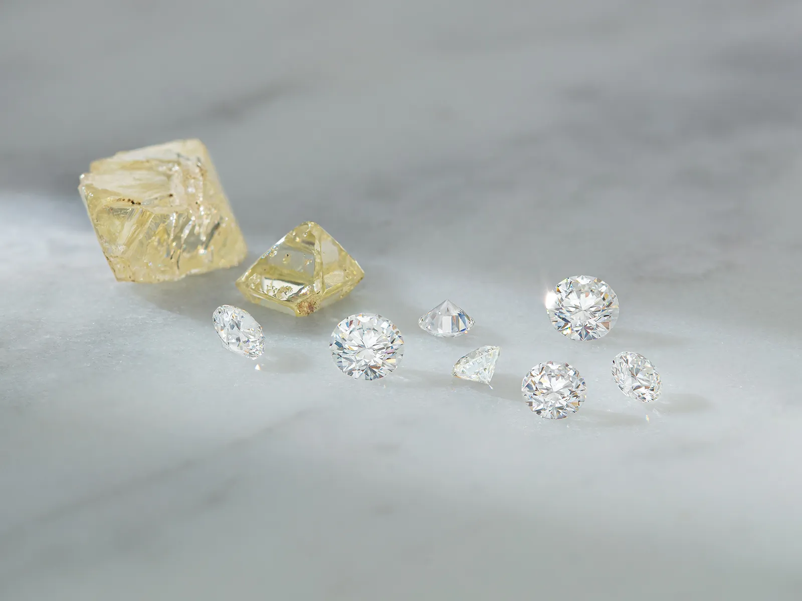 A collection of raw and cut diamonds on a marble surface.