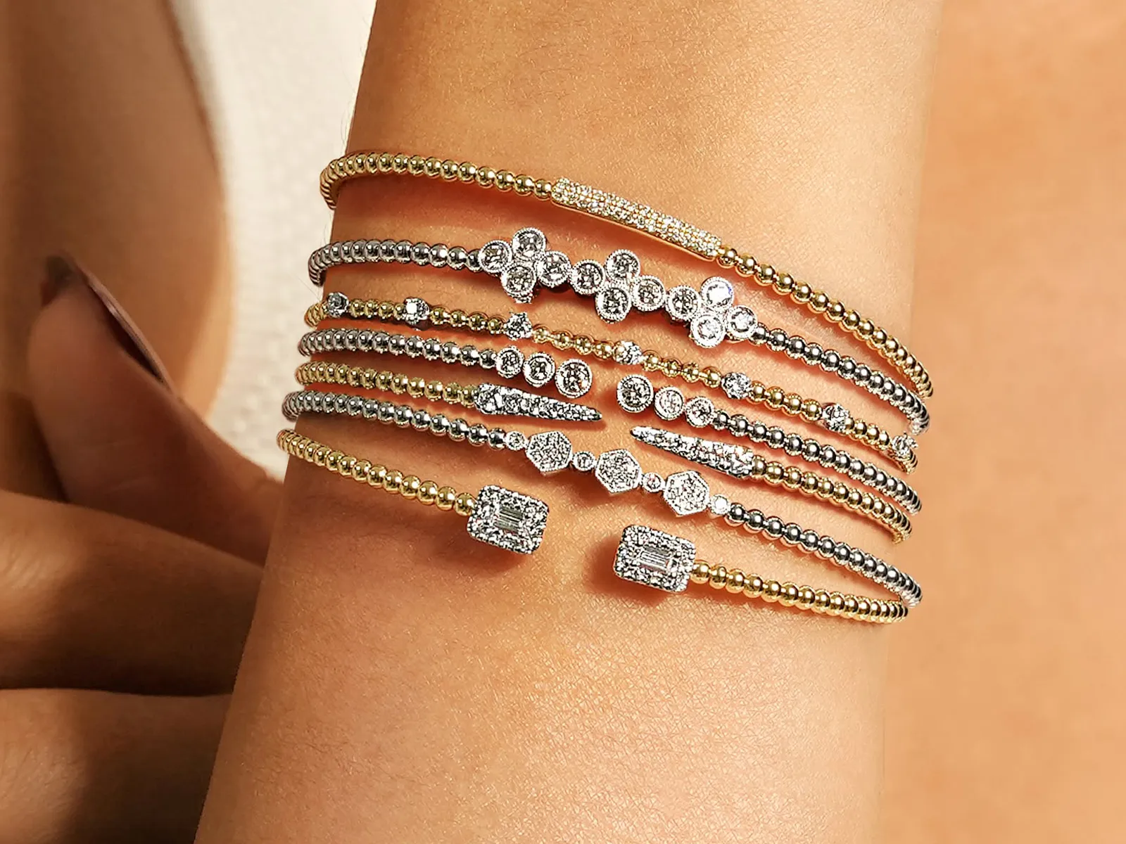 Stacked gold and silver diamond bracelets on a wrist.