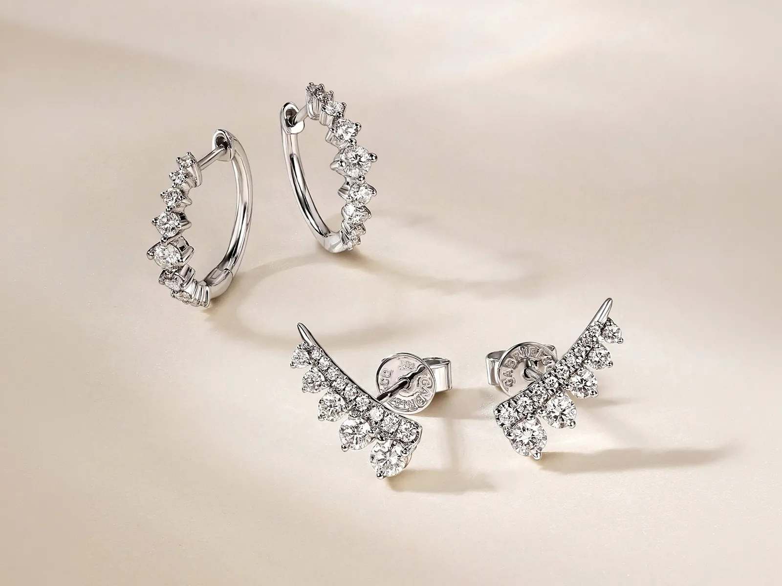 Diamond hoop and stud earrings with sparkling stones on a light background.