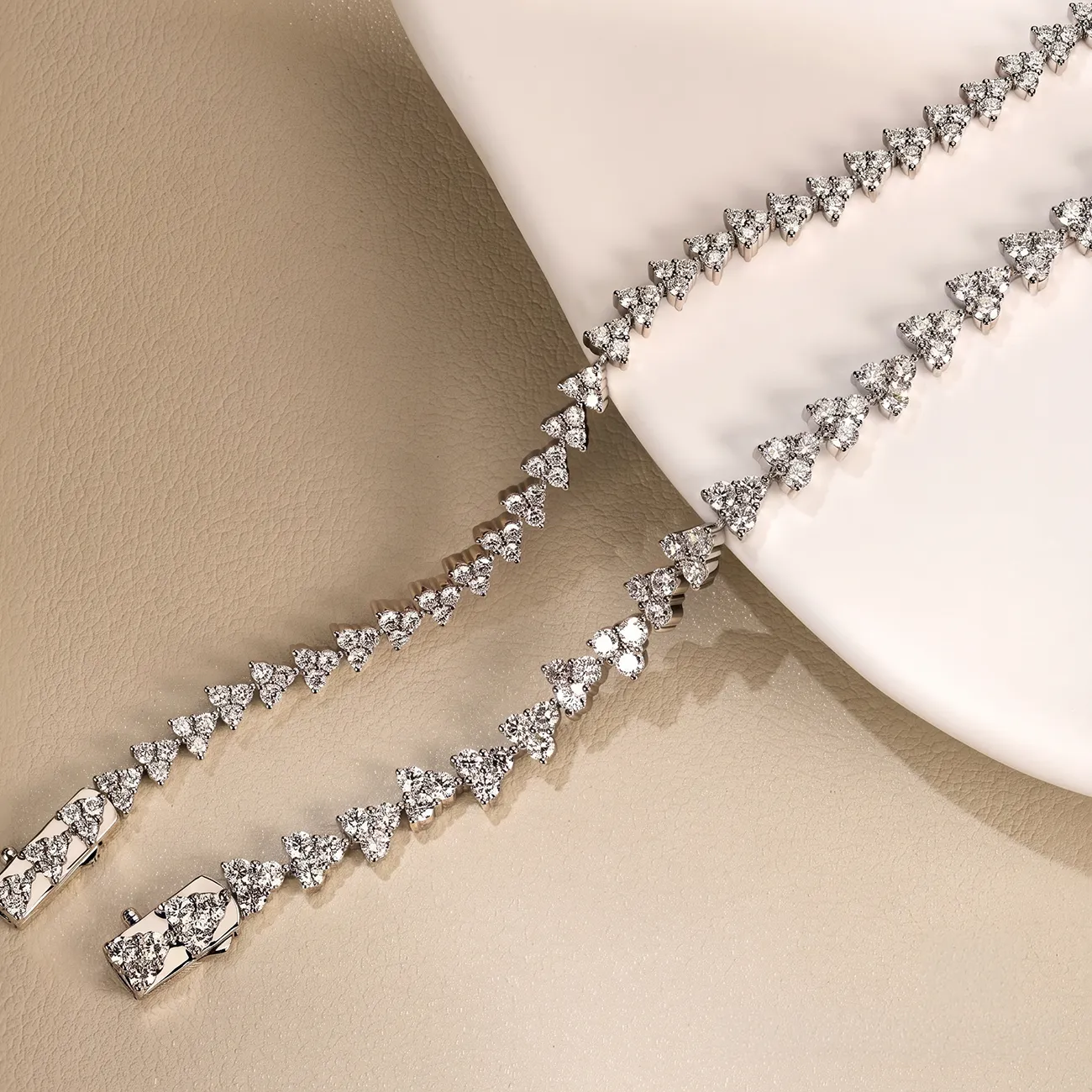 A diamond necklace with triangular clusters on a beige surface.