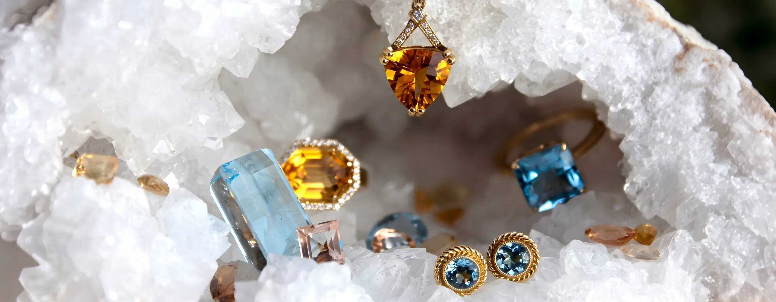 Jewelry pieces with blue and yellow gemstones displayed on white crystals.