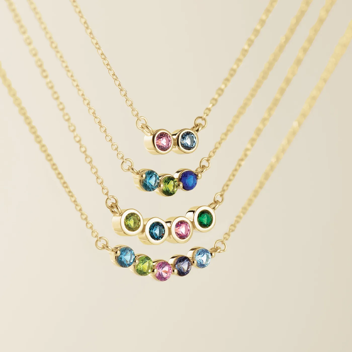 Four gold necklaces with colorful gemstones arranged in increasing order of stones.