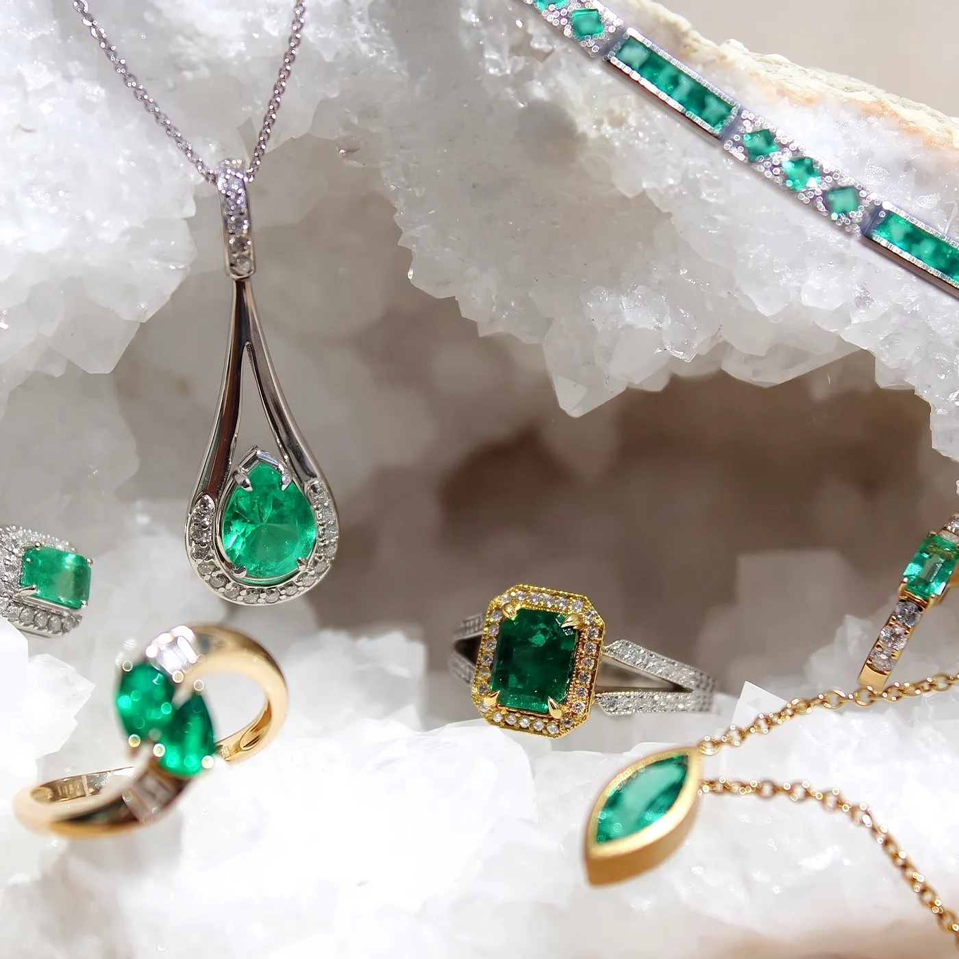 Emerald jewelry collection displayed on a white crystal background.