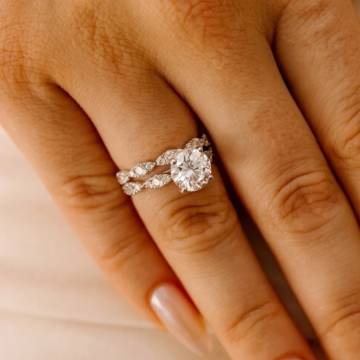 A hand wearing a diamond engagement ring with a twisted band design.
