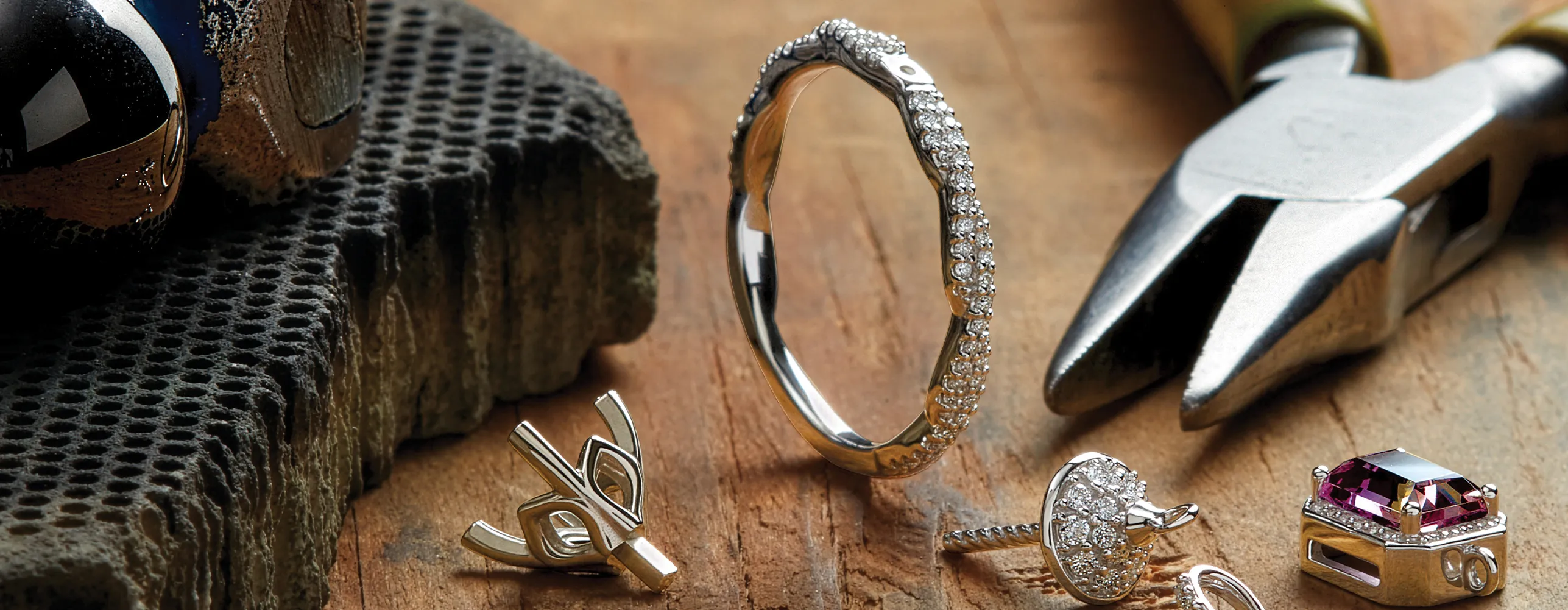 Jewelry tools and diamond rings on a wooden surface.