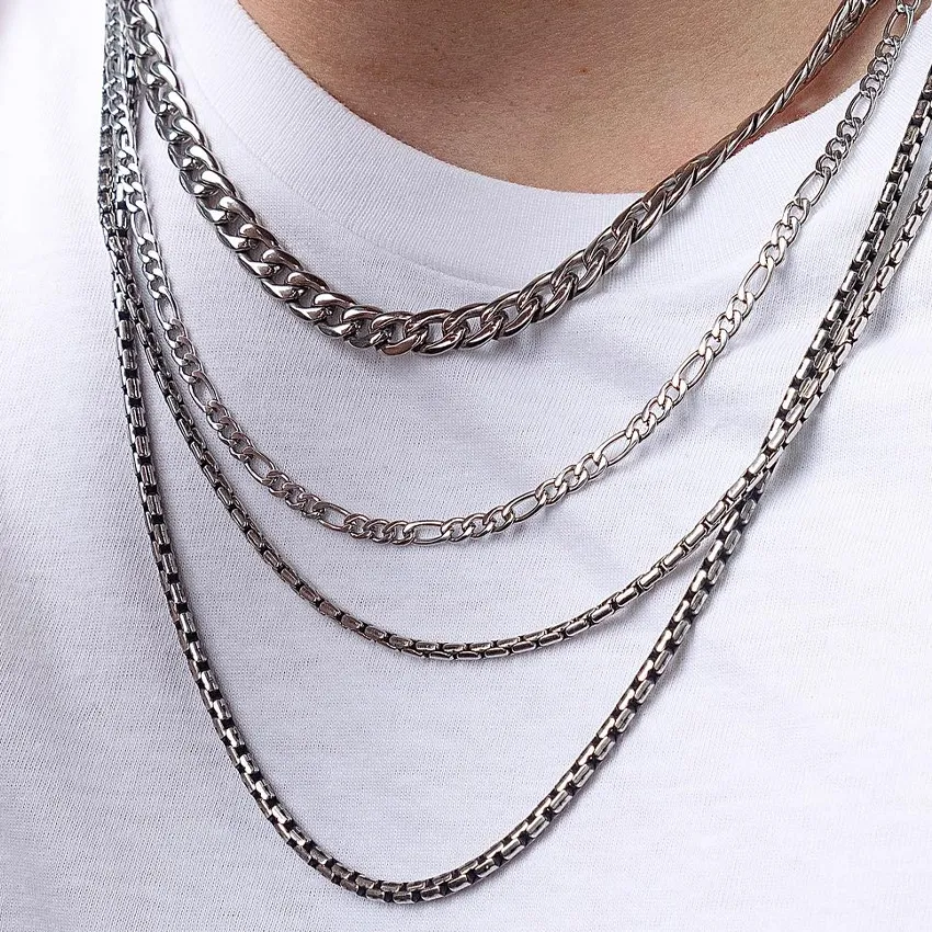 Silver chains layered on a white shirt, showcasing INOX jewelry.