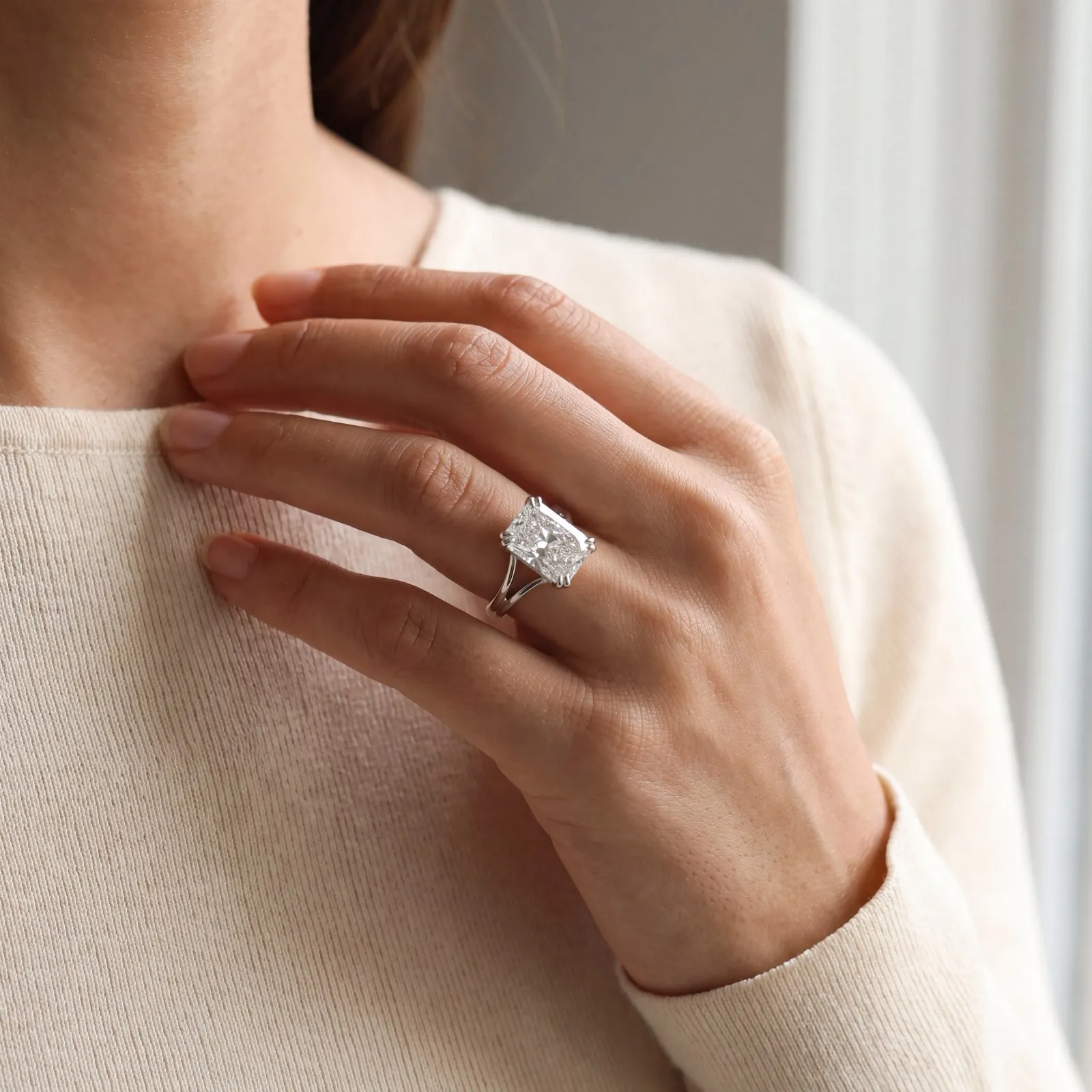 Oval diamond ring with halo setting on a hand.