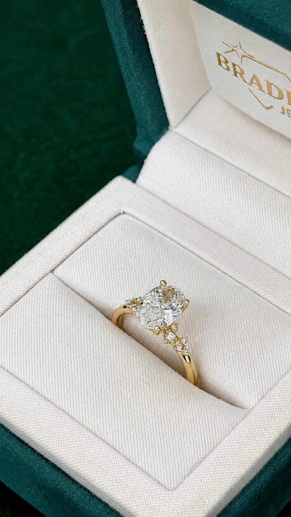 Gold ring with emerald and diamonds in a white jewelry box at Bradley's Jewelers, Jacksonville.