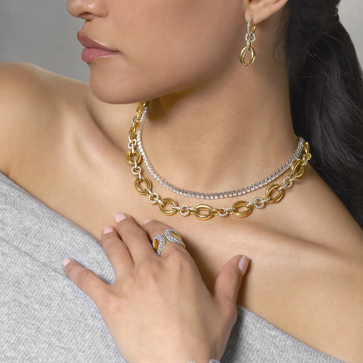 Woman wearing gold and diamond jewelry: necklace, earrings, and ring.
