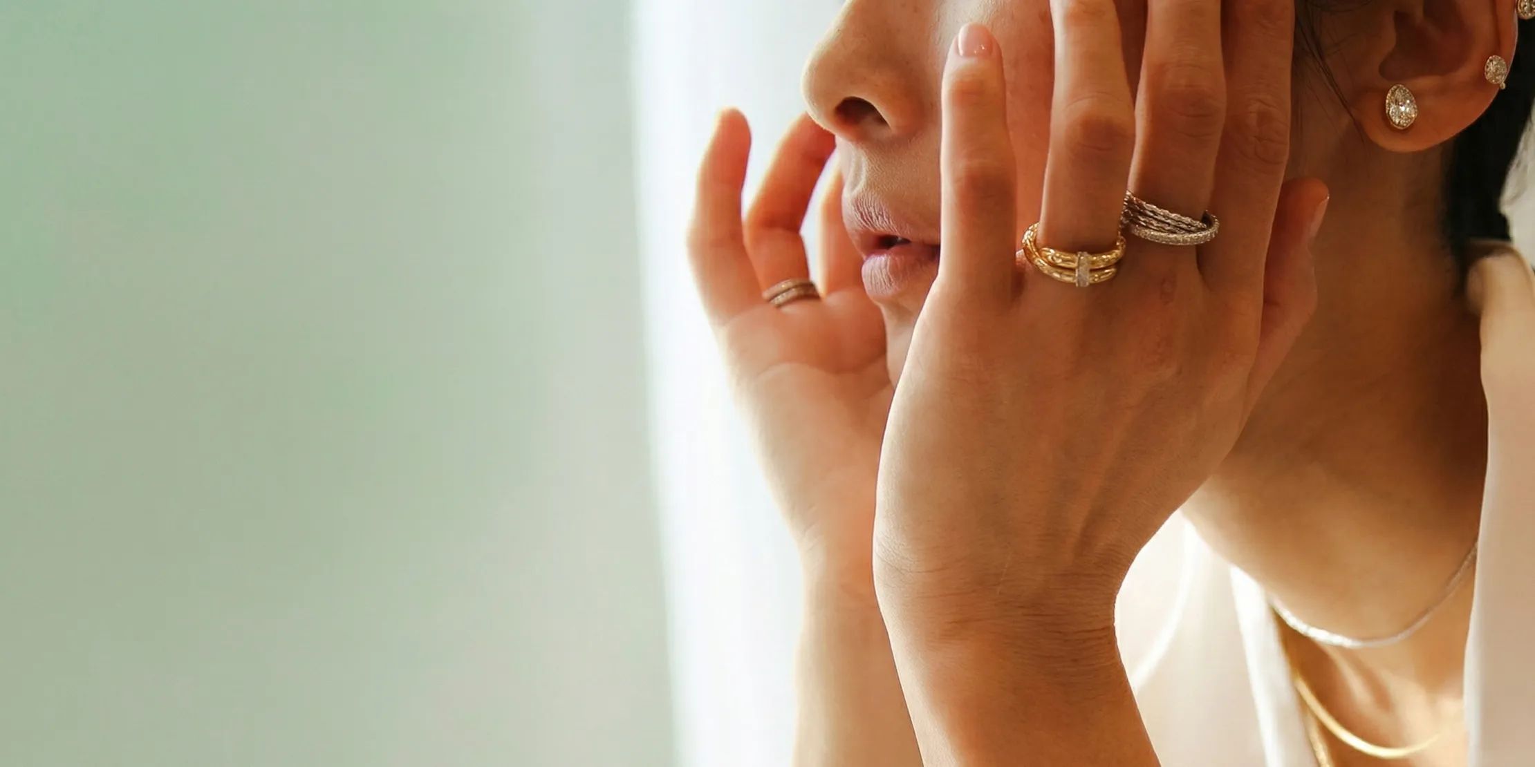 Hands with rings touching face, showcasing jewelry.