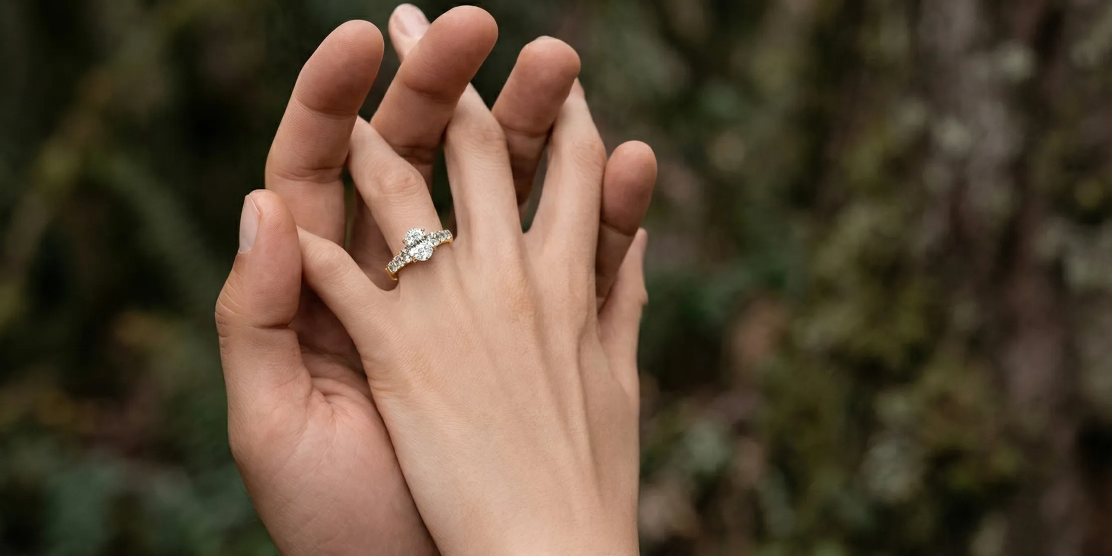 Two hands intertwined, one wearing a diamond ring.