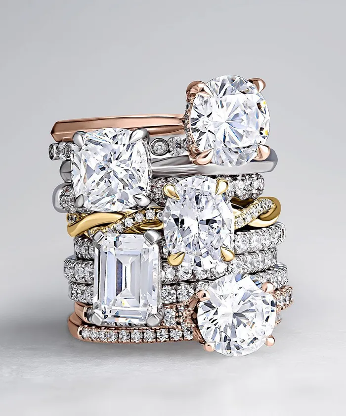 A stack of elegant diamond rings in various styles and metals, showcasing fine jewelry craftsmanship.