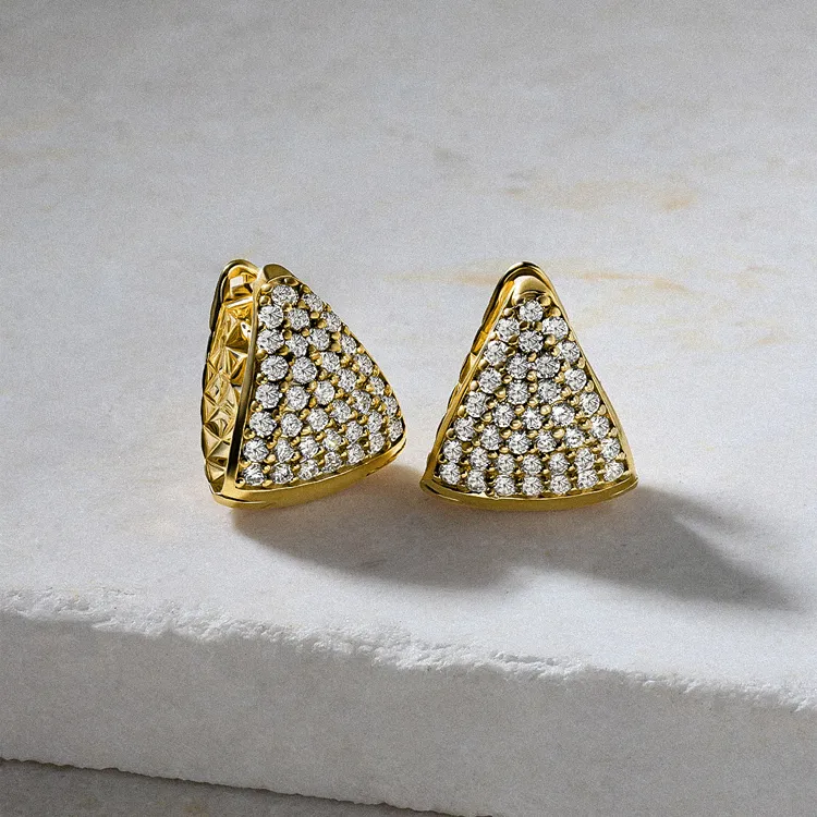 Gold triangular earrings with diamond clusters on a marble surface.