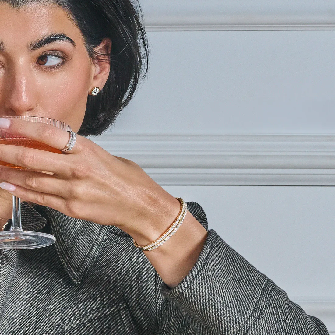 Woman sipping drink, wearing diamond bracelet and ring.