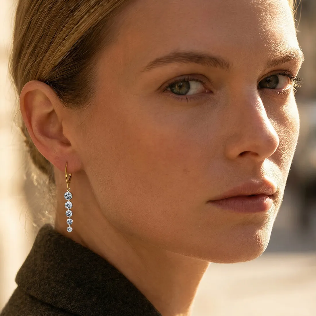 Close-up of a person wearing gold earrings with multiple diamonds.