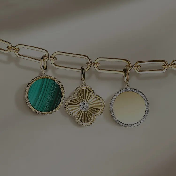 Three gold charms with intricate designs on a chain.