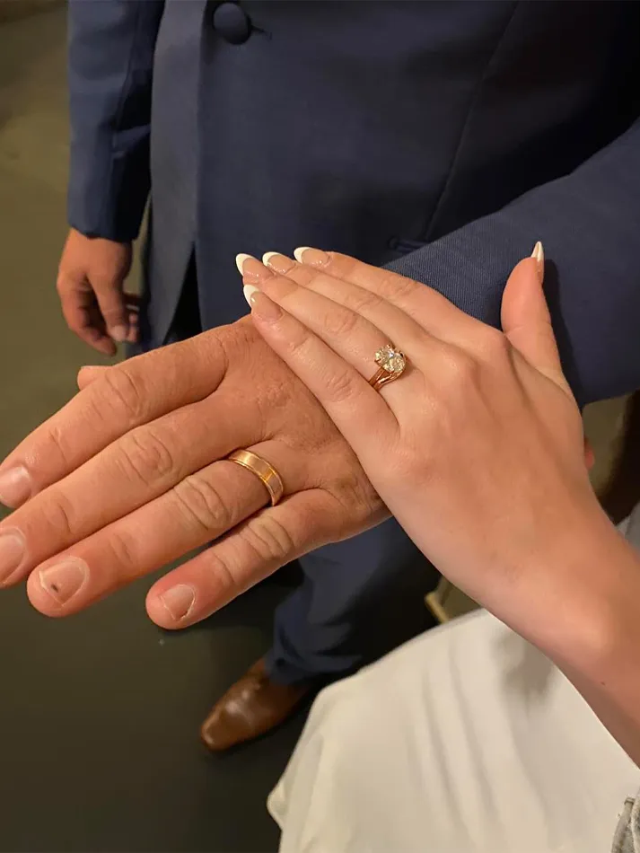 Hands with wedding rings, one with a diamond, symbolizing marriage.