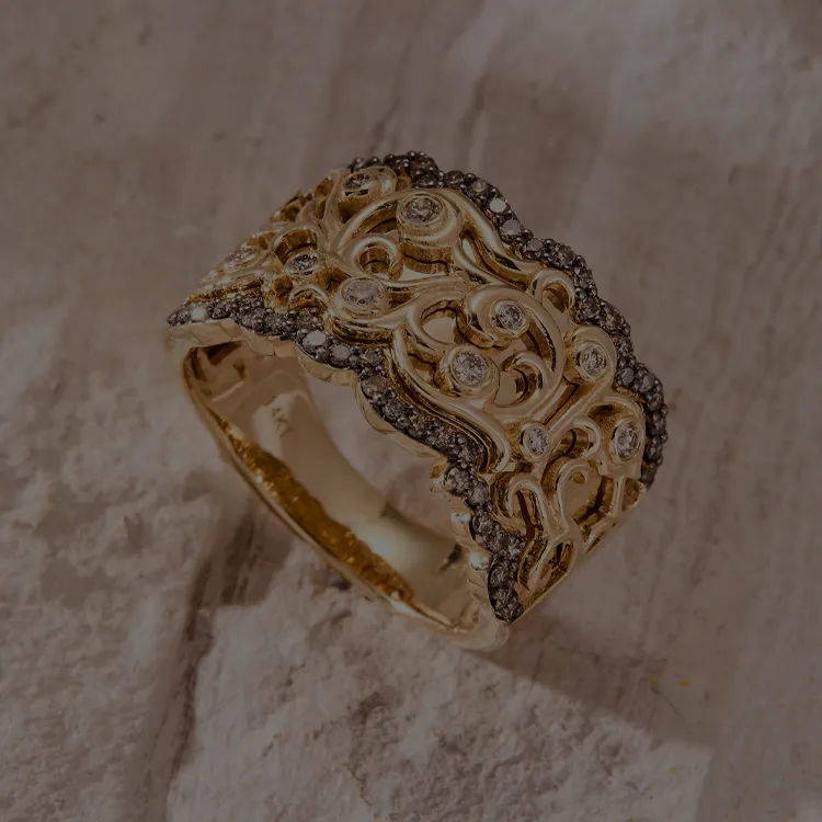 Intricate gold ring with diamond accents on a textured surface.