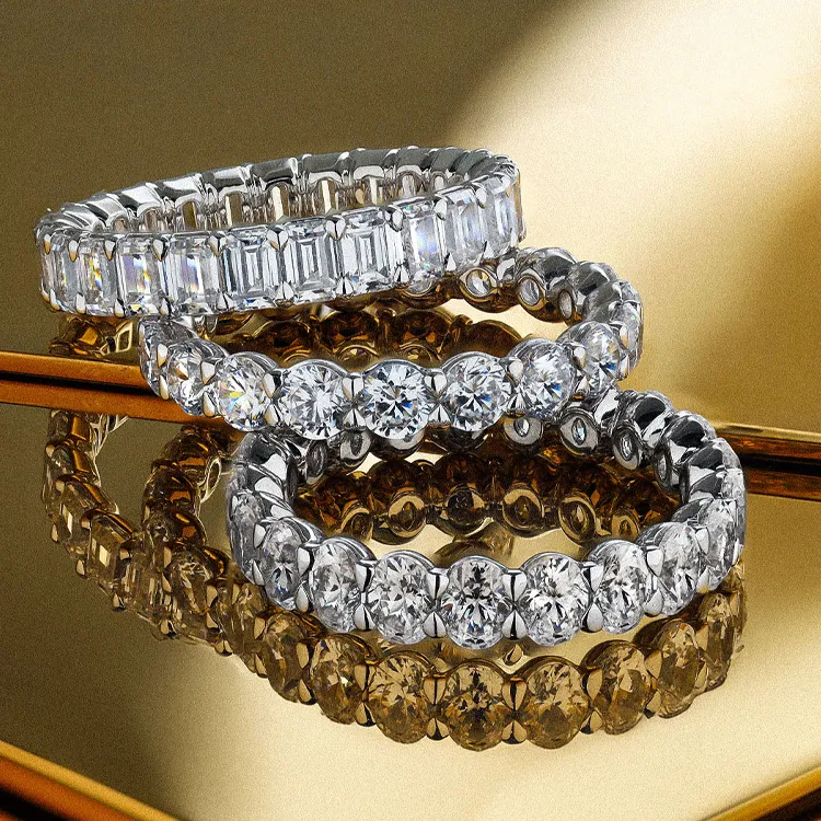 Three diamond wedding bands on a reflective surface.