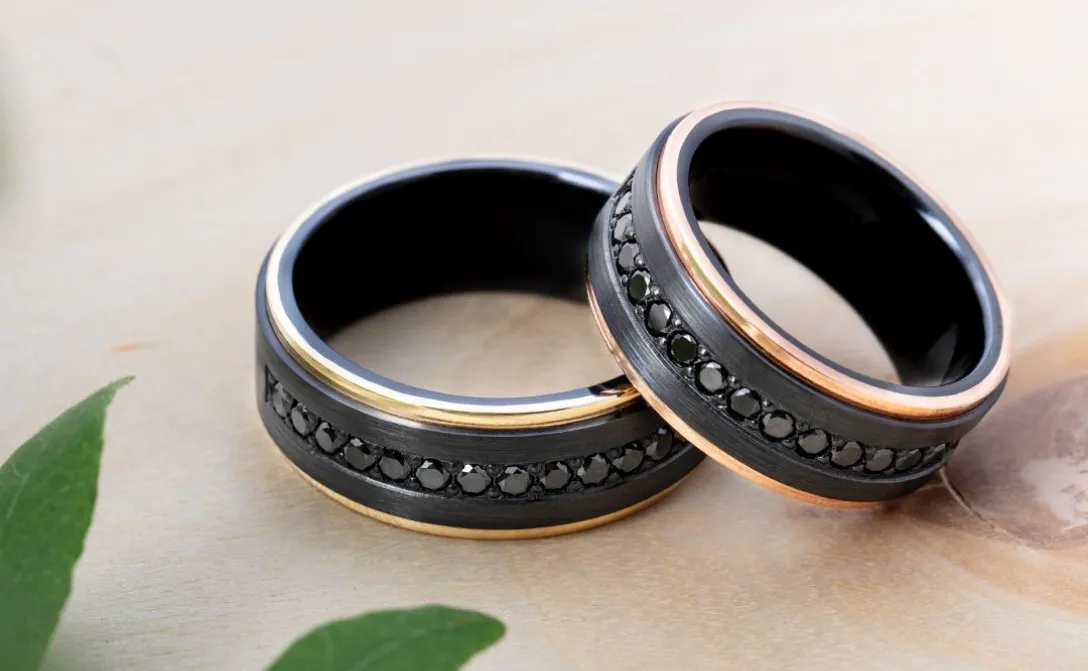Two stylish black rings with gold and rose gold accents, featuring black gemstones.