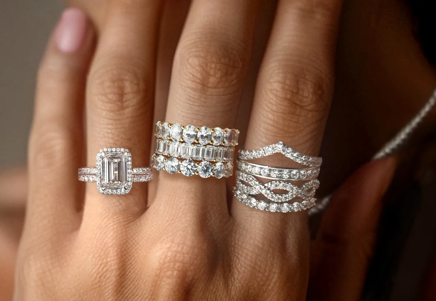Three elegant diamond rings displayed on a hand, showcasing various styles and settings.