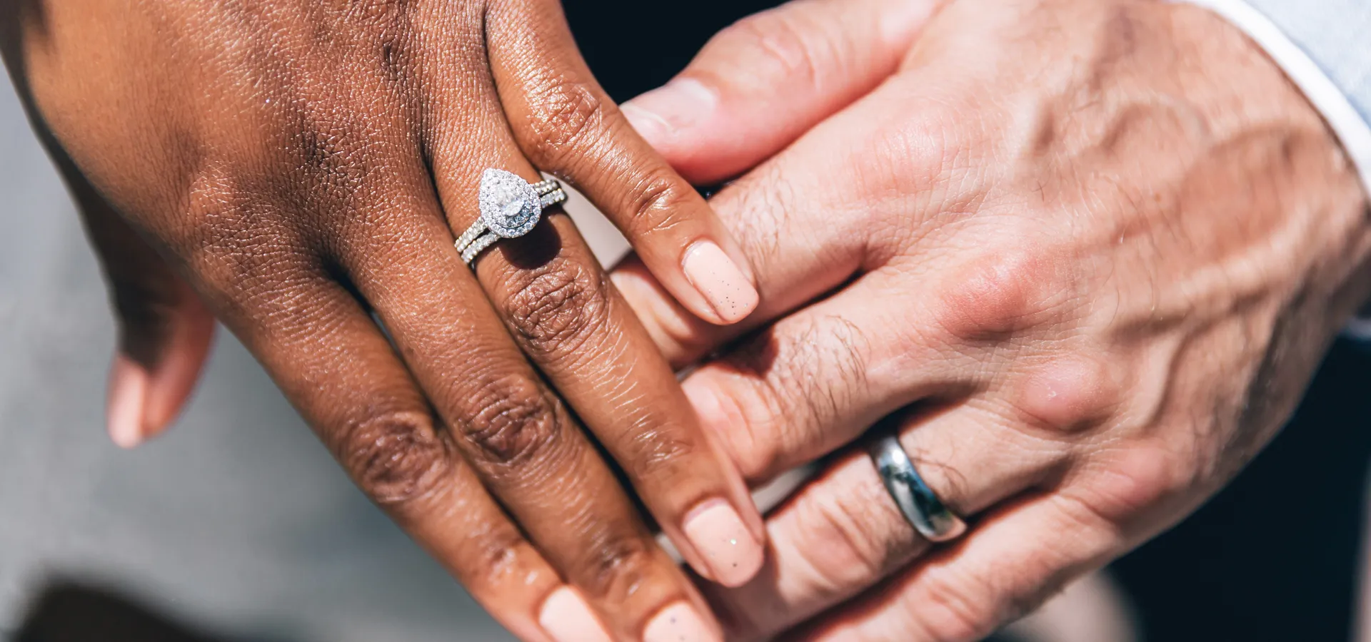 Close-up of two hands, one with a diamond engagement ring, symbolizing love and commitment.