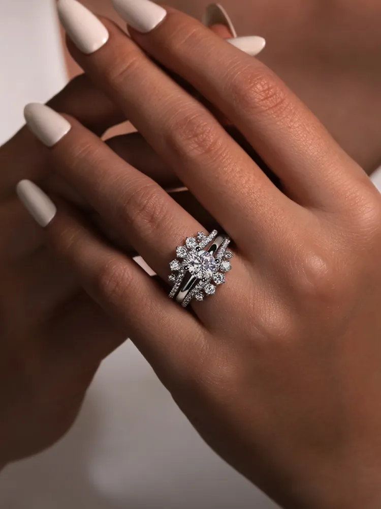Elegant hand wearing a diamond bridal ring set, showcasing intricate designs and sparkling stones. 