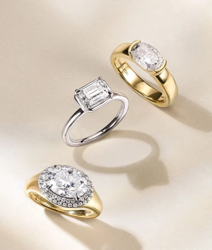 Three elegant diamond rings featuring different styles: oval, emerald cut, and halo design, displayed on a soft background.