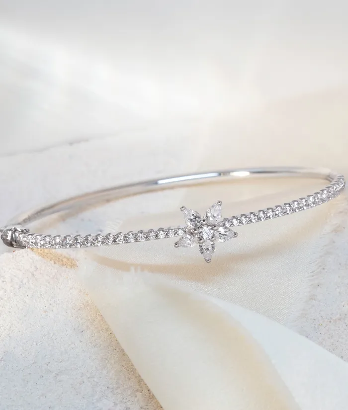 Silver bangle bracelet with a star-shaped diamond centerpiece, perfect for elegant occasions. 
